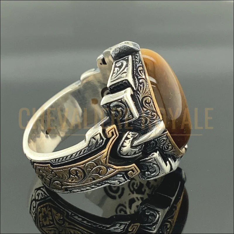 Optez pour la sophistication avec notre chevalière en argent massif, mettant en avant une pierre œil de tigre de 15 x 20 mm. Cette bague artisanale, réalisée à la main, combine une forme ovale élégante à des vertus protectrices et énergétiques. Parfaite pour un cadeau unique ou pour ajouter une touche distinctive à votre collection de bijoux, elle offre un mélange de style et de signification profonde.-Chevaliere Royale-854